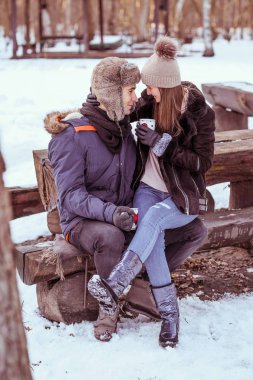 Genç çift ormanda sıcak çikolata açık içiyor.