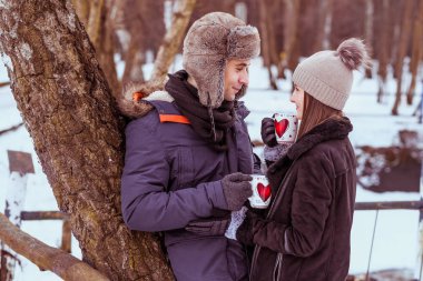 Genç çift ormanda sıcak çikolata açık içiyor.