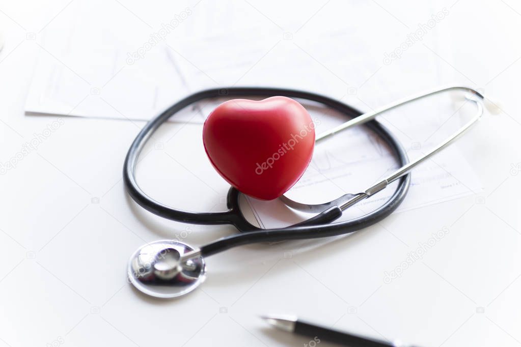 Stethoscope and heart lying on the white desk.