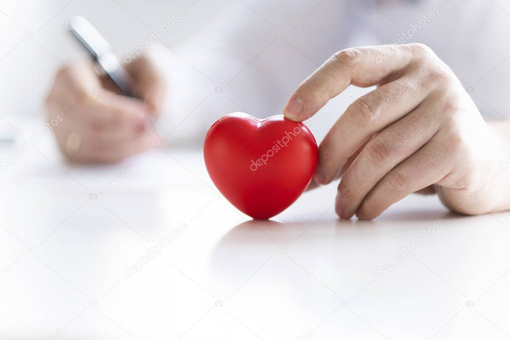 The doctor is holding a heart in the hands. Heart is a life!