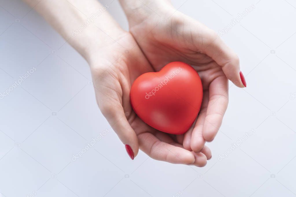 Red heart on female hand.