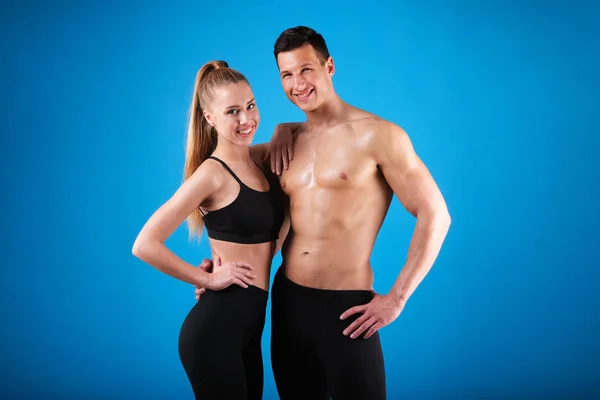 Fitness young man and woman isolated on blue background.