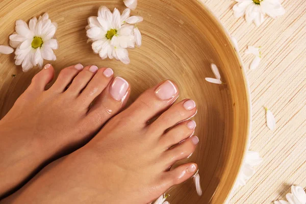 The picture of ideal done manicure and pedicure. Female hands and legs in the spa spot.