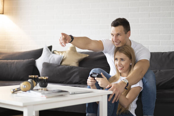Young couple is having fun while playing the game on tv.
