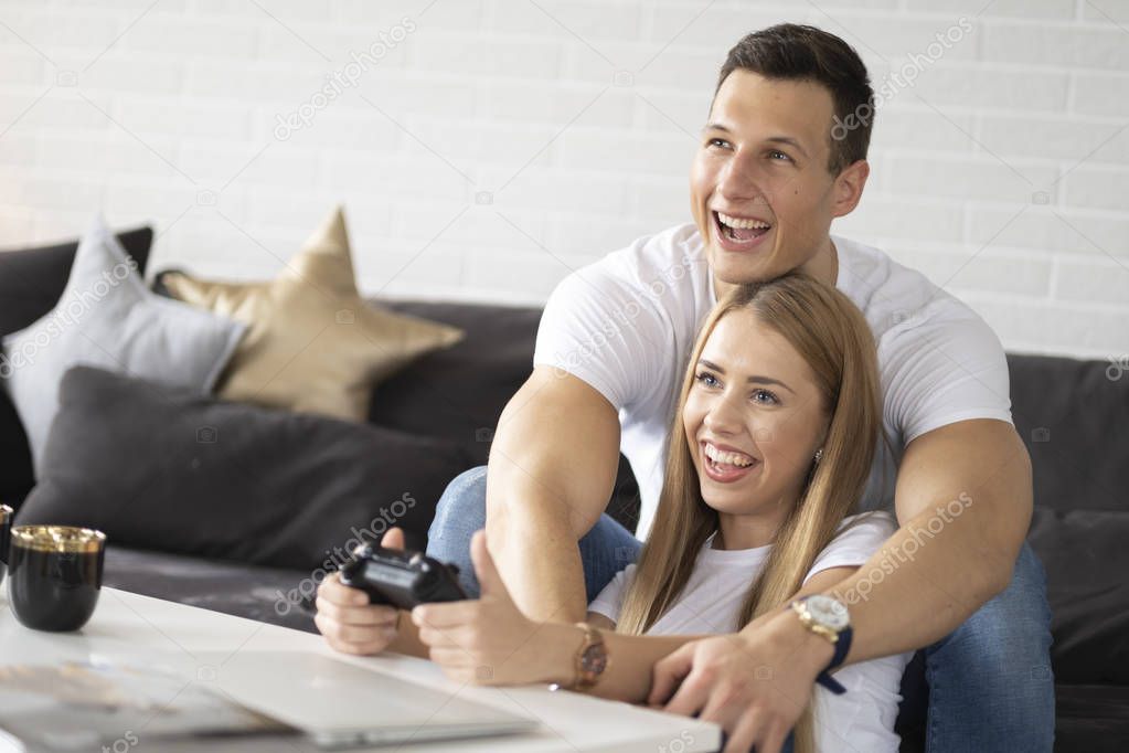 Young couple is having fun while playing the game on tv.