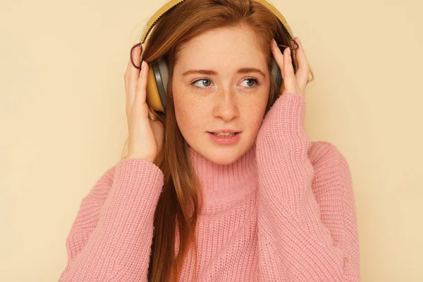 Beauty shoot of young fresh, full of energy girl with ginger hair listening to music.