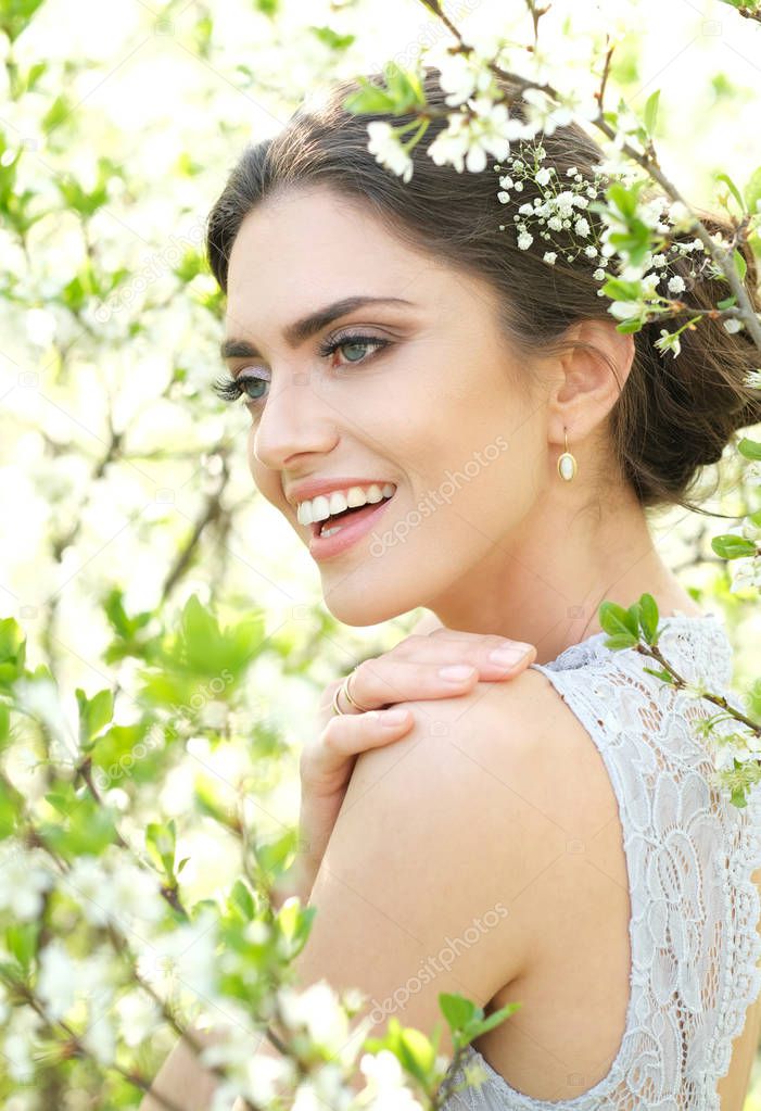 Shoot of beautiful smiling woman in blossoming bushes.