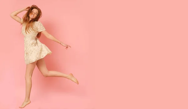 美丽的姜女孩跳高 孤立在粉红色背景 — 图库照片