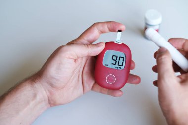 Diyabet hastası adam, glucometer ile glikoz seviyesini kontrol ediyor.