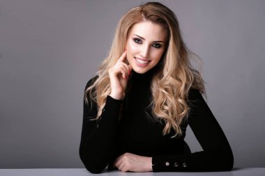 Gri arka planda nazik bir gülümseme ile güzel kadın.