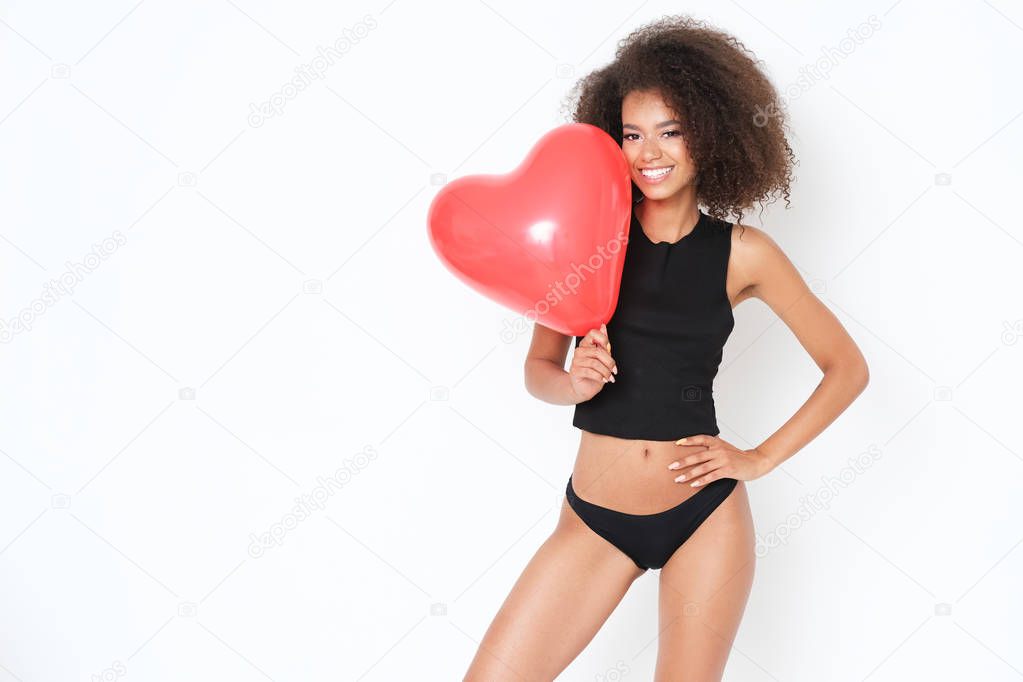 Sexy young woman in black top posing with heart shape balloon.
