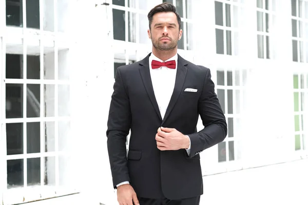 Classy look is always the best. Man wearing a black suit and red bow-tie.