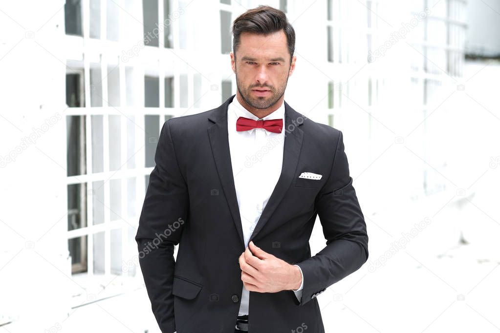 Classy look is always the best. Man wearing a black suit and red bow-tie.