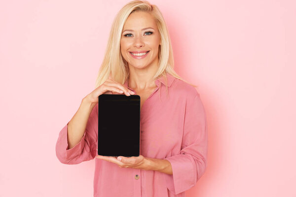Красивая женщина в розовом фоне представляет цифровой планшет
.