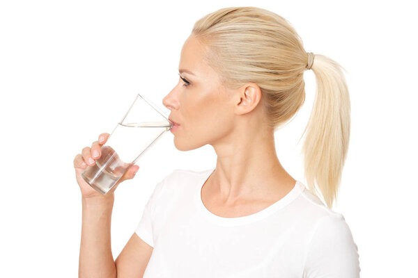 Profile picture of healthy and pretty woman drinking a glass of water. Model is isolated on white background.