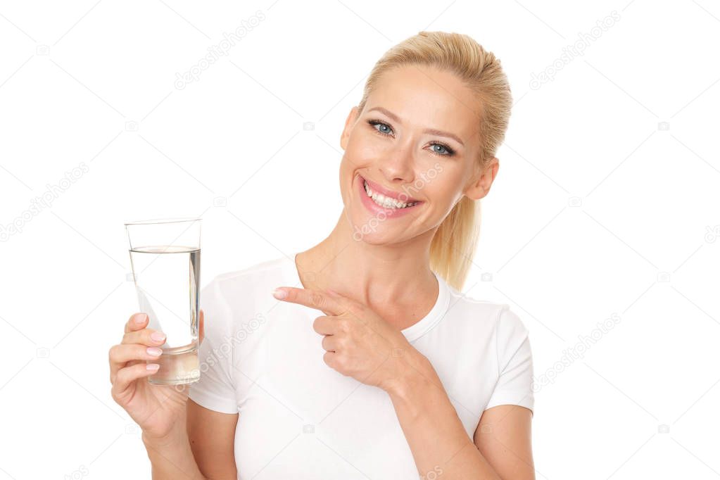 Healthy blonde woman  points a finger at glass of water.