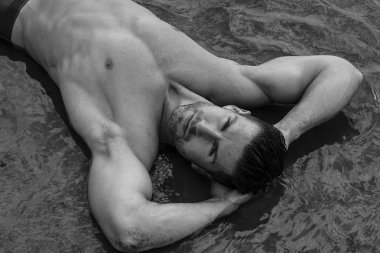 Mayo giymiş, suda poz veren kaslı vücutlu yakışıklı adam..