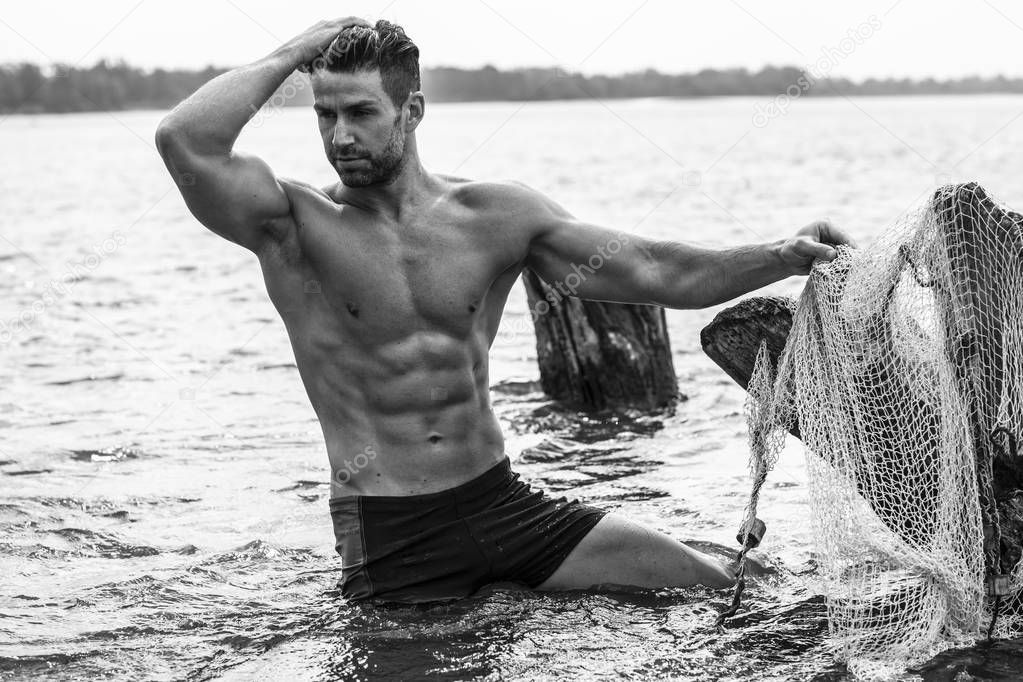 Hot body man posing in swimwear outdoors. 