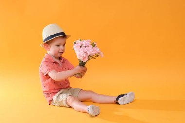 Bir demet çiçekli küçük sevimli çocuk. Tatil havası var.! 