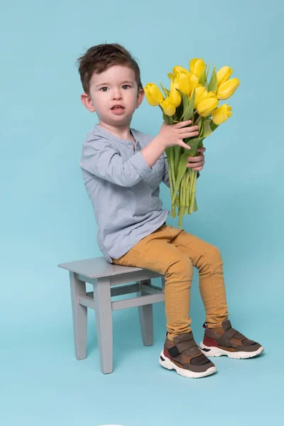 Söt Liten Pojke Med Bänk Gula Tulpaner Studiosession — Stockfoto