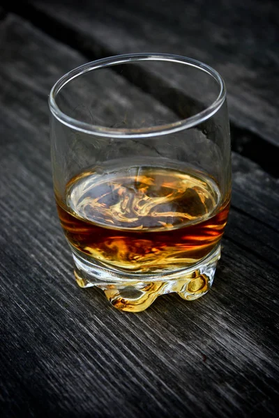 Close up of a whiskey glass on a wooden table