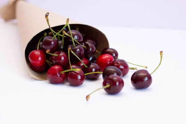 Ripe cherries in a paper bag on a white background, summer harvest — Stock Photo, Image