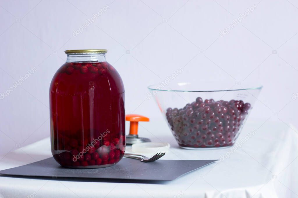cherry compote in a glass jar for the winter, preparing food for storage, cherries in a transparent cup