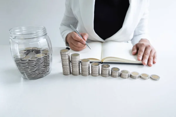 Mujer escribir monedas a mano en el banco de botellas de vidrio con gráfico de barras de monedas, intensificar el negocio creciente para el éxito y el ahorro para el concepto de jubilación — Foto de Stock