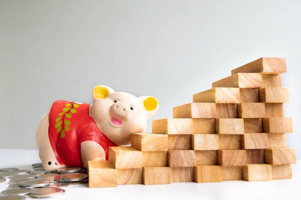 Red piggy bank saving money with coins pile and wood graph