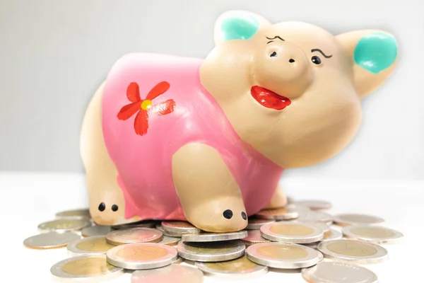 pink piggy bank saving money and coins pile