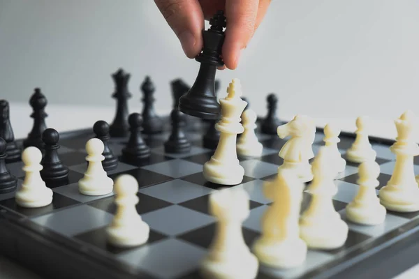 hand of businessman moving chess in competition, shows leadership, followers and business success strategies