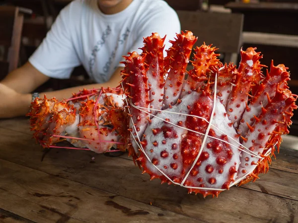 Mulher com dois caranguejos rei Alaska congelado pronto na mesa de madeira para cozinhar — Fotografia de Stock