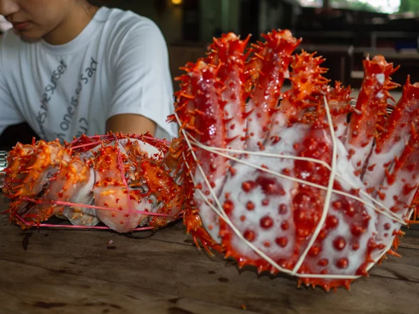 Mulher com dois caranguejos rei Alaska congelado pronto na mesa de madeira para cozinhar — Fotografia de Stock