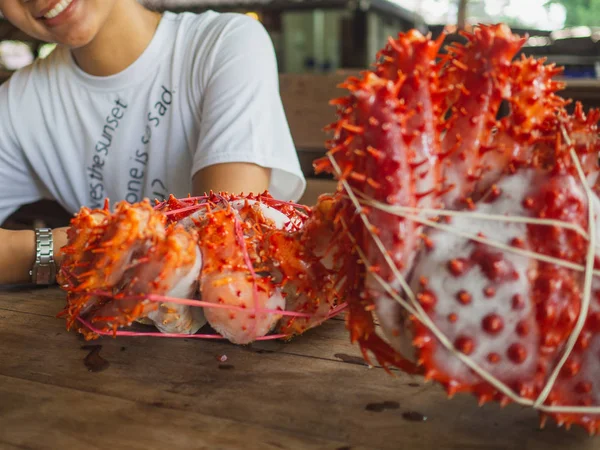 Mulher com dois caranguejos rei Alaska congelado pronto na mesa de madeira para cozinhar — Fotografia de Stock