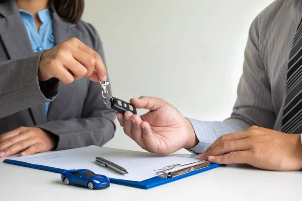 Concessionnaire automobile fournit des conseils sur les détails de l'assurance et des informations de location de voiture et livre les clés après la signature du contrat de location — Photo