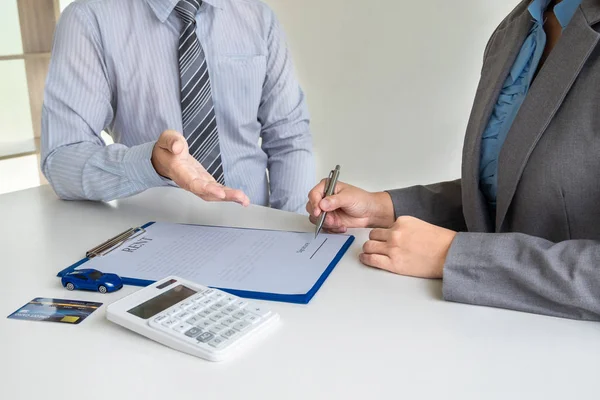 Car dealership provides advice about insurance details and car rental information and delivers the keys after signing the rental contract