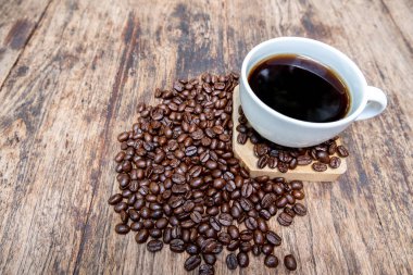 kahve çekirdekleri bir fincan siyah kahve ile kahverengi ahşap arka plan üzerinde çanta dökülen dolu