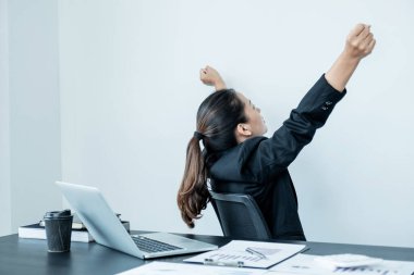 Ofiste çalışan genç bir kadın. Sırtı yere dönük, rahat, kolları havada..