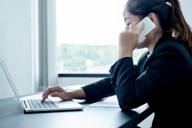 Bir iş adamı kız telefonda gülümsüyor. Masa başında oturmuş, ofiste çalışan modern bir bilgisayarı açıyor..