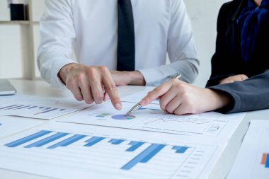 Sonuçları gösteren çizelge ve grafikleri tartışan iki iş lideri ofiste büyük başarı için yeni bir strateji başlatmayı planlıyor..