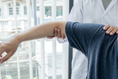 Kadın fizyoterapistler, erkek hastalara omuz sakatlığı olan hastalar için rehabilitasyon merkezinde omuzlarına masaj yapıyorlar. Fizyoterapi kavramları.