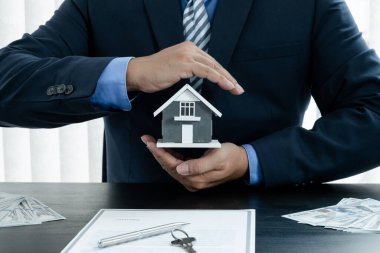 Ev, müşteriler, ev sahipleri ve sigortacılar için evi korumak için bir emlakçının ellerinde, yeni sahibine vermeye hazır. Ev sigortası satış kavramı.