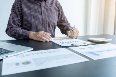 Bir erkek işadamının elleri, ofisteki bakiyeleri özetlemek amacıyla mali bir grafikte yıllık gelir ve giderleri analiz ediyor ve hesaplıyor..