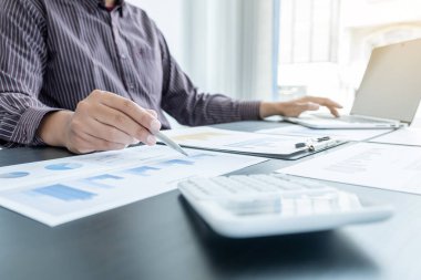 Bir erkek işadamının elleri, ofisteki bakiyeleri özetlemek amacıyla mali bir grafikte yıllık gelir ve giderleri analiz ediyor ve hesaplıyor..