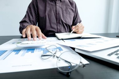 Bir erkek işadamının elleri, ofisteki bakiyeleri özetlemek amacıyla mali bir grafikte yıllık gelir ve giderleri analiz ediyor ve hesaplıyor..