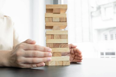 İş kadınının elleri tahta blokları engeller, kumar oynar, tahta bloklar yerleştirir. Ticari büyüme ve başarı için yönetim riski ve strateji planlarını kabul et.