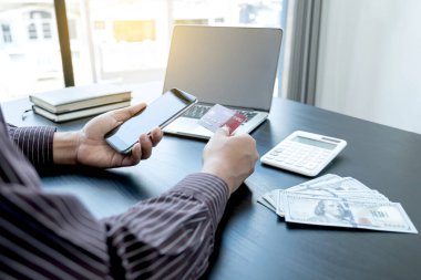 İş adamının elinde bir kredi kartı var ve internet üzerinden alışveriş ve internet üzerinden ödeme yapmak için akıllı telefon kullanıyor..