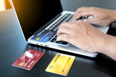 İş adamının elinde bir kredi kartı var ve ofisteki online alışveriş ve internet ödemeleri için dizüstü bilgisayar kullanıyor..