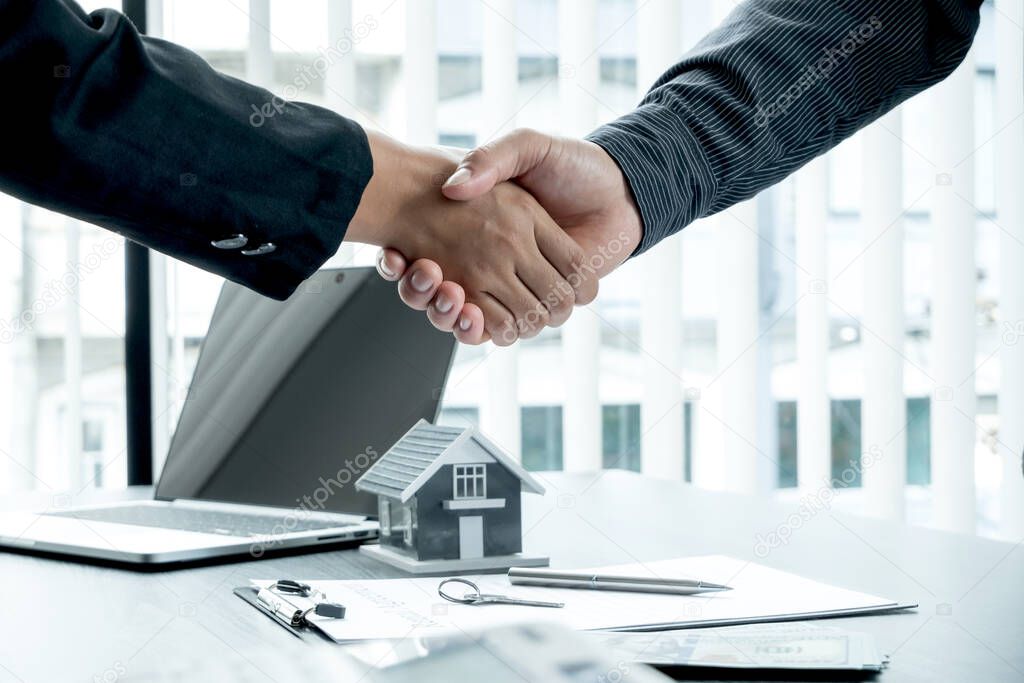 A real estate agent and clients shake hands after completing the home insurance contract negotiation and signing a formal contract. Rental and home insurance concepts.