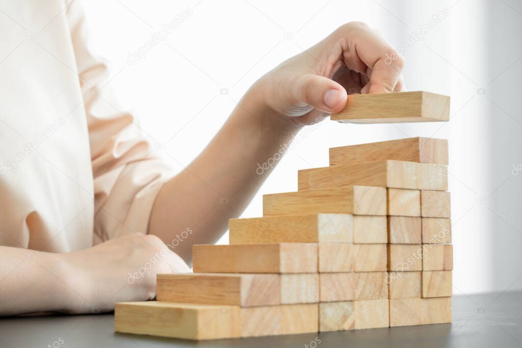 Hands of businesswomen playing wooden block game. Concept Risk of management and strategy plans for business growth and success.